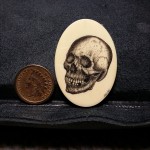 Skull scrimshaw by Jason Webb - finished skull scrimshaw with coin to the left shown for scale