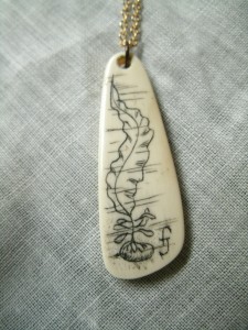 scrimshaw on pendant of what appears to be kelp under water