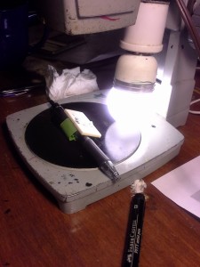 Alternative ivory propped up on a pen and held in place with a piece of masking tape with the sticky side out. The angle reflects the polished surface into the low power microscope's aperature