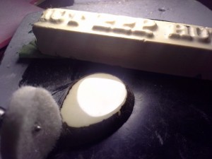 Polished tagua nut (center), HUT wax bar (top) and dremel felt wheel (bottom left)